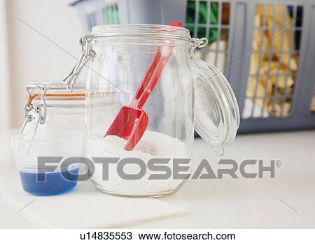 Stock Image - Detergent and washing powder by laundry basket. Fotosearch