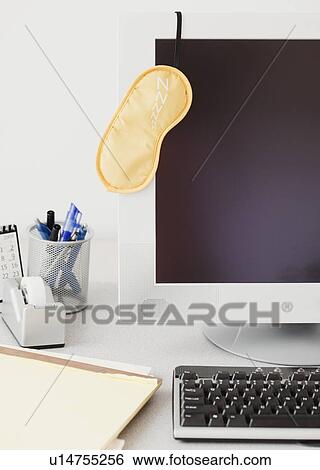 Stock Photograph - Eye mask hanging on computer monitor. Fotosearch