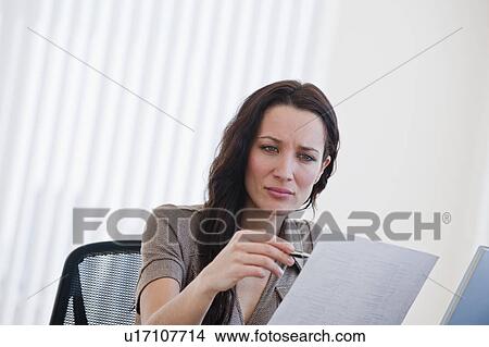 Picture - Female office worker reading document. Fotosearch