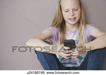 Stock Photo - Girl (10-12) sitting and text messaging. Fotosearch