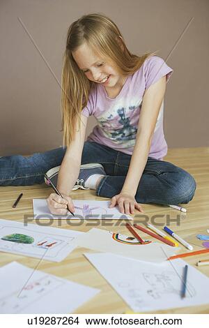 Picture - Girl (10-12) sitting on floor and drawing pictures. Fotosearch