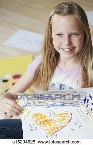 Stock Photography - "Girl (10-12) sitting on floor and showing her picture, portrait". Fotosearch