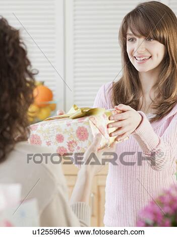 Girl (10-12 years) receiving birthday present from mother View Large Photo Image Stock Photography - Girl (10-12 years) receiving birthday present from mother. Fotosearch