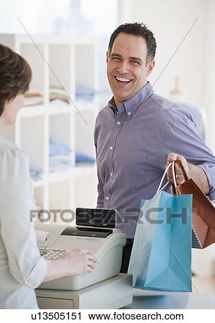 Man at checkout counter with bags View Large Photo Image Stock Image - Man at checkout counter with bags. Fotosearch