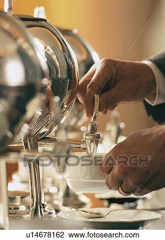 Stock Image - Man pouring tea from samovar. Fotosearch