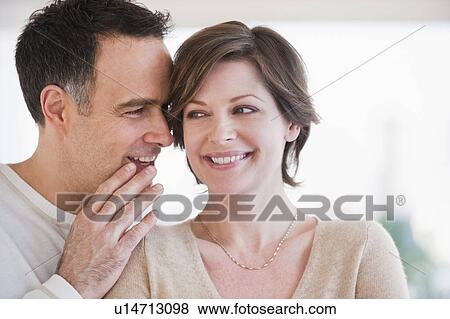 Stock Photo - Man whispering to woman's ear. Fotosearch