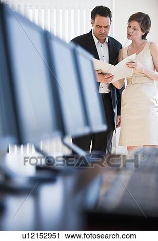 Stock Image - Mature businesswoman and businessman reading document. Fotosearch