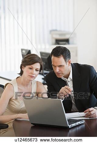 Stock Image - Mature businesswoman and businessman working together in office. Fotosearch