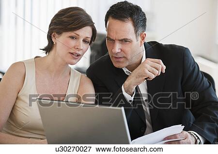 Stock Photo - Mature businesswoman and businessman working together in office. Fotosearch