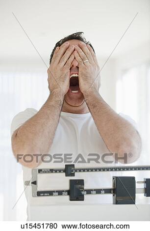 Mature man on scales screaming and covering his eyes View Large Photo Image Stock Image - Mature man on scales screaming and covering his eyes. Fotosearch