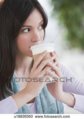 Stock Image - Mid-adult woman drinking from plastic cup. Fotosearch
