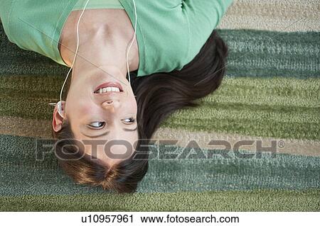 Mid-adult woman lying on floor and listening to music View Large Photo Image Stock Image - Mid-adult woman lying on floor and listening to music. Fotosearch