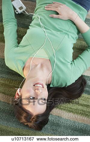 Mid-adult woman lying on floor and listening to music View Large Photo Image Stock Photo - Mid-adult woman lying on floor and listening to music. Fotosearch