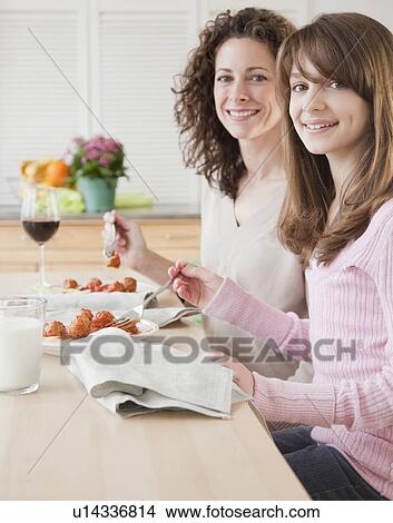 "Mother and daughter (10-12 years) eating dinner, portrait" View Large Photo Image Picture - "Mother and daughter (10-12 years) eating dinner, portrait". Fotosearch