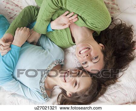 "Mother and daughter (10-12 years) lying on bed, smiling, portrait, directly above" View Large Photo Image Stock Image - "Mother and daughter (10-12 years) lying on bed, smiling, portrait, directly above". Fotosearch