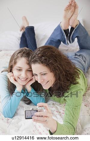 Stock Photograph - Mother and daughter (10-12 years) photographing self with digital camera. Fotosearch