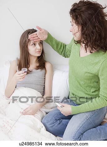 Picture - Mother measuring daughter's (10-12 years) fever. Fotosearch
