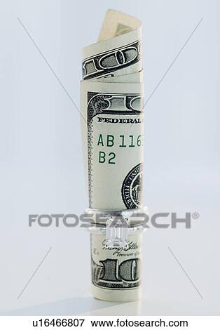 Stock Photo - One hundred dollar bill rolled up in wedding ring. Fotosearch