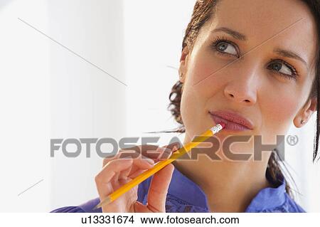 Picture - Pensive business woman holding pencil. Fotosearch