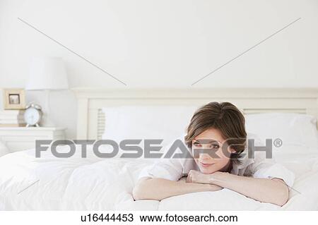 Stock Image - Pensive woman relaxing on bed. Fotosearch