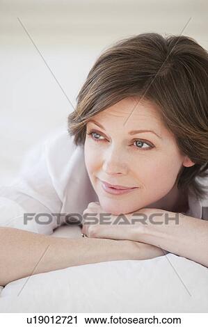 Stock Image - Pensive woman relaxing on bed. Fotosearch