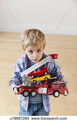 Portrait of boy (3-4) holding toy fire engine and cars View Large Photo Image Picture - Portrait of boy (3-4) holding toy fire engine and cars. Fotosearch