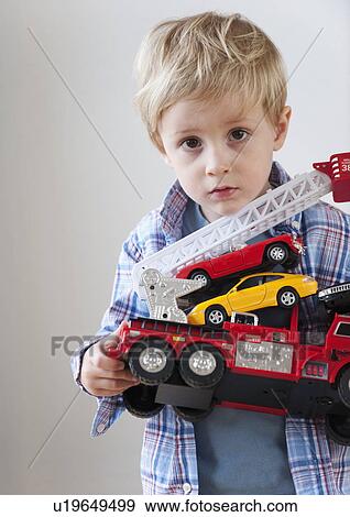 Stock Photo - Portrait of boy (3-4) holding toy fire engine and cars. Fotosearch