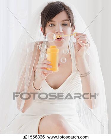 Stock Photograph - Portrait of bride blowing bubbles. Fotosearch