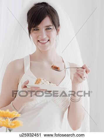 Stock Image - Portrait of bride eating wedding cake. Fotosearch