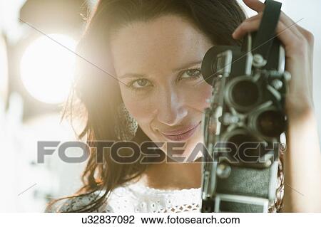 Stock Image - Portrait of female filmmaker using film camera. Fotosearch