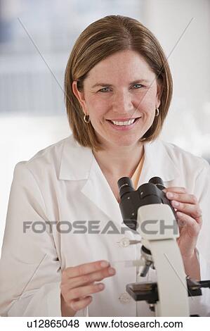 Stock Photo - Portrait of female scientist using microscope. Fotosearch