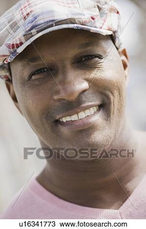 Stock Image - "Portrait of man wearing cap, smiling". Fotosearch