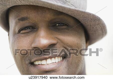 Stock Image - "Portrait of man wearing hat, smiling". Fotosearch