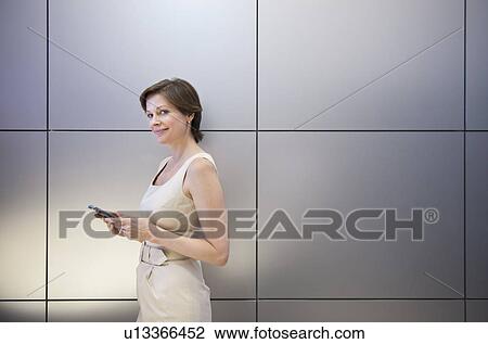 Stock Image - Portrait of mature businesswoman holding mobile phone. Fotosearch