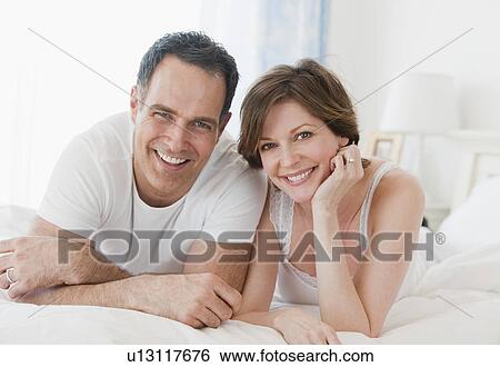 Stock Photograph - "Portrait of mature couple in bed, smiling". Fotosearch