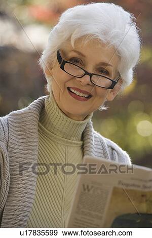 Portrait of senior woman reading newspaper outdoors View Large Photo Image Stock Photo - Portrait of senior woman reading newspaper outdoors. Fotosearch