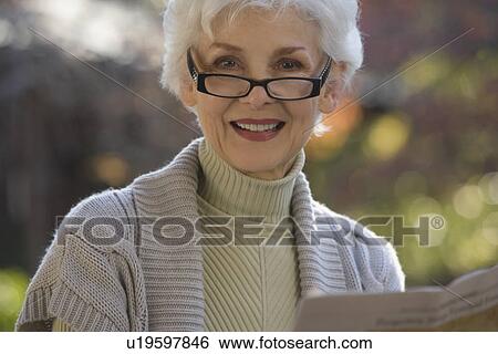 Portrait of senior woman reading newspaper outdoors View Large Photo Image Stock Photograph - Portrait of senior woman reading newspaper outdoors. Fotosearch