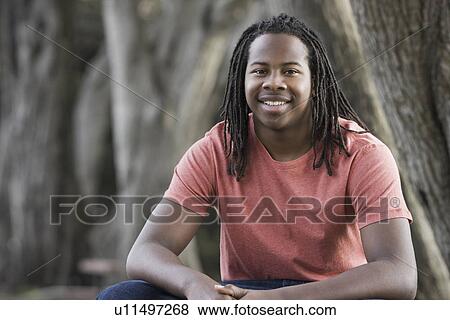 "Portrait of teenage boy (16-17) with dreadlocks, sitting in park" View Large Photo Image Stock Photo - "Portrait of teenage boy (16-17) with dreadlocks, sitting in park". Fotosearch