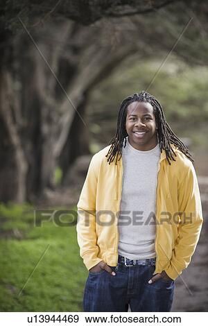 Stock Photo - "Portrait of teenage boy (16-17) with dreadlocks, smiling in park". Fotosearch