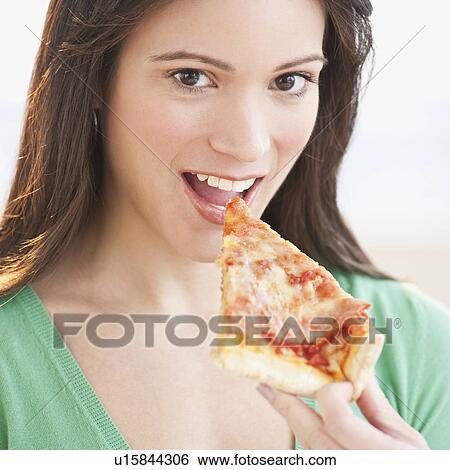 Stock Photograph - Portrait of woman eating pizza slice. Fotosearch