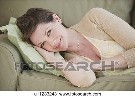 Stock Image - Portrait of woman on sofa. Fotosearch