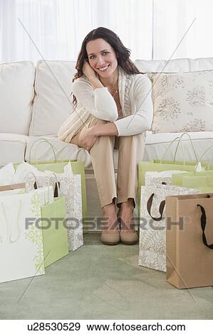 Portrait of woman sitting on sofa with shopping bags View Large Photo Image Stock Photo - Portrait of woman sitting on sofa with shopping bags. Fotosearch