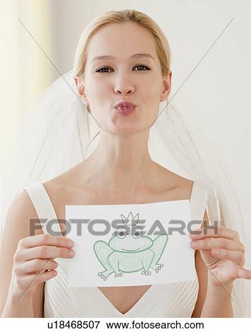 Portrait of young bride blowing kiss and holding drawing of frog prince View Large Photo Image Stock Photo - Portrait of young bride blowing kiss and holding drawing of frog prince. Fotosearch