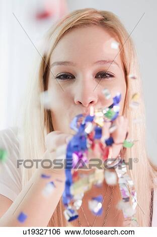 Portrait of young woman blowing confetti View Large Photo Image Stock Photograph - Portrait of young woman blowing confetti. Fotosearch