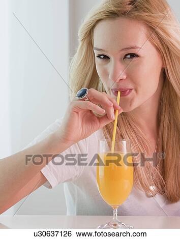 Portrait of young woman drinking orange juice View Large Photo Image Stock Photograph - Portrait of young woman drinking orange juice. Fotosearch