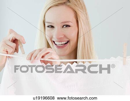 Stock Photo - Portrait of young woman hanging laundry on washing line. Fotosearch