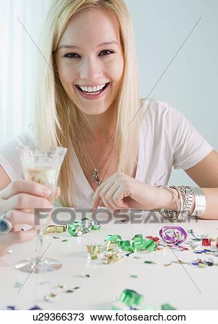 Stock Image - Portrait of young woman holding champagne and new year's eve. Fotosearch
