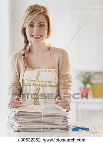 Portrait of young woman recycling newspaper in kitchen View Large Photo Image Stock Image - Portrait of young woman recycling newspaper in kitchen. Fotosearch