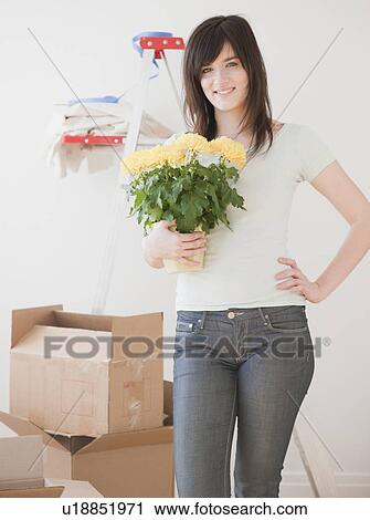 Stock Image - Portrait of young woman redecorating new house. Fotosearch