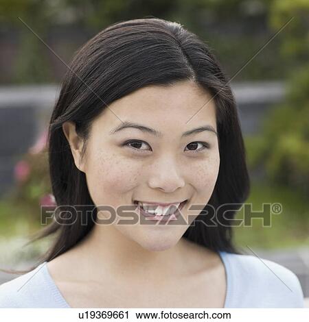 Stock Image - "Portrait of young woman smiling, outdoors". Fotosearch